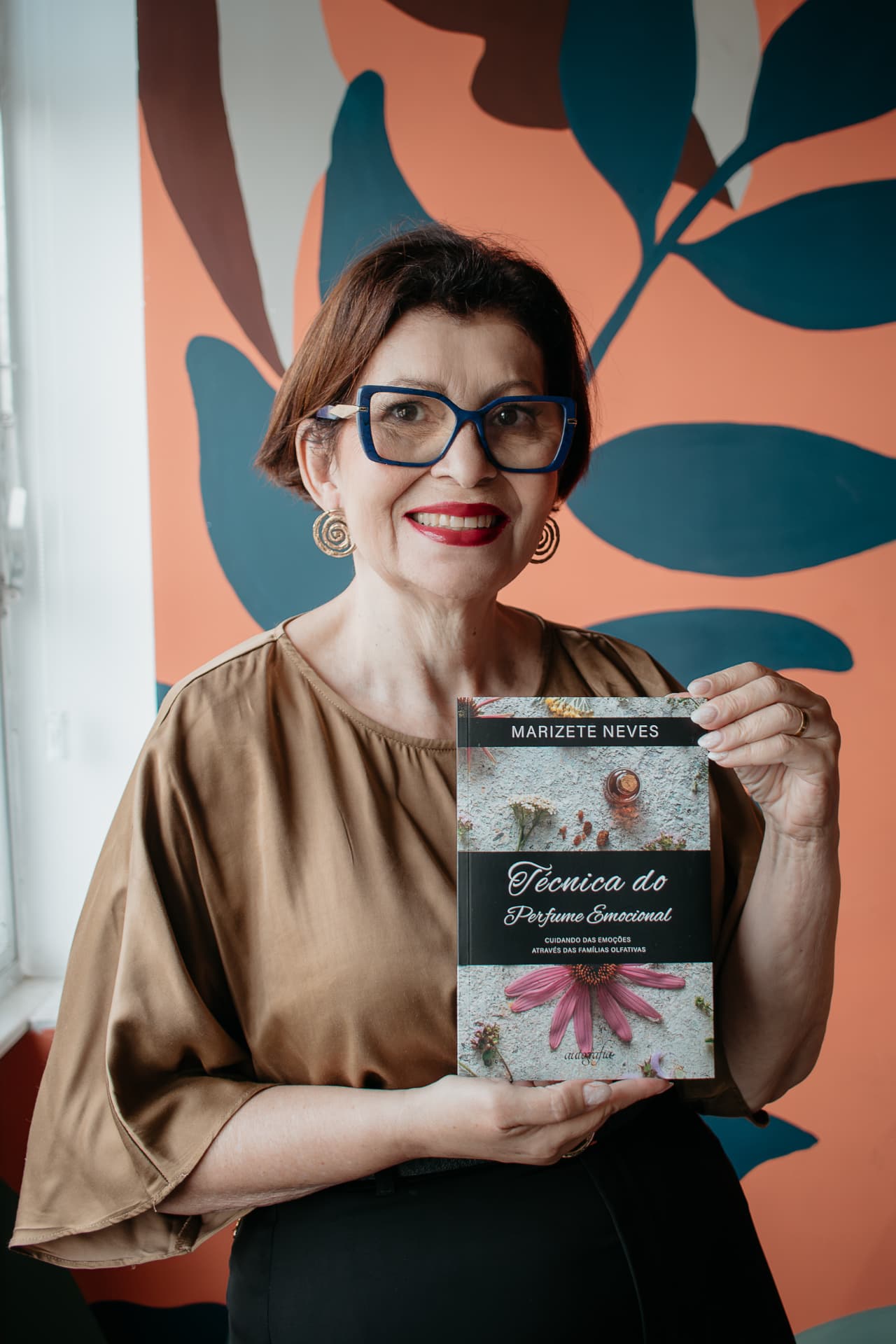 Marizete Neves segurando seu livro Técnica do Perfume Emocional